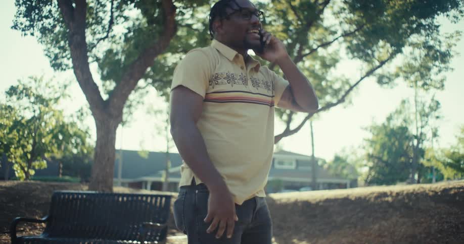 A cheerful man celebrates excitedly while talking on the phone outdoors