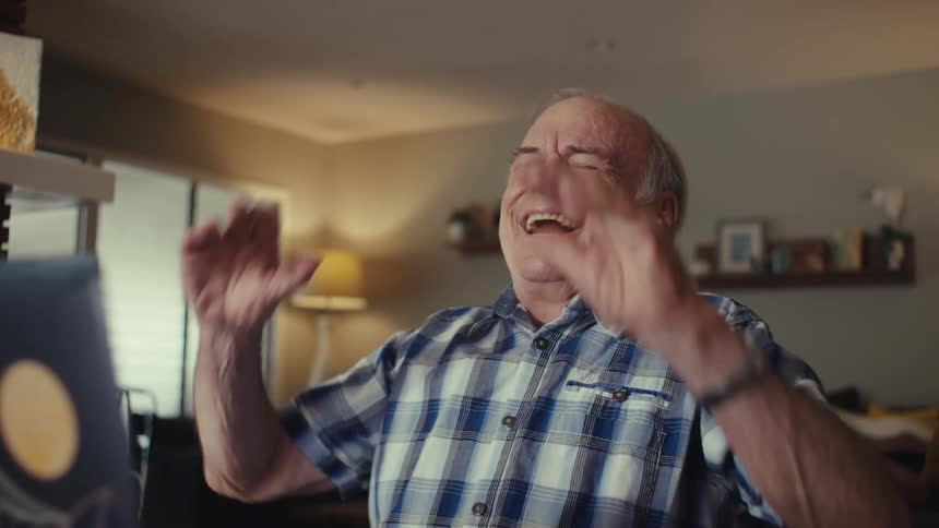 Elderly man sitting in a living room with a happy expression