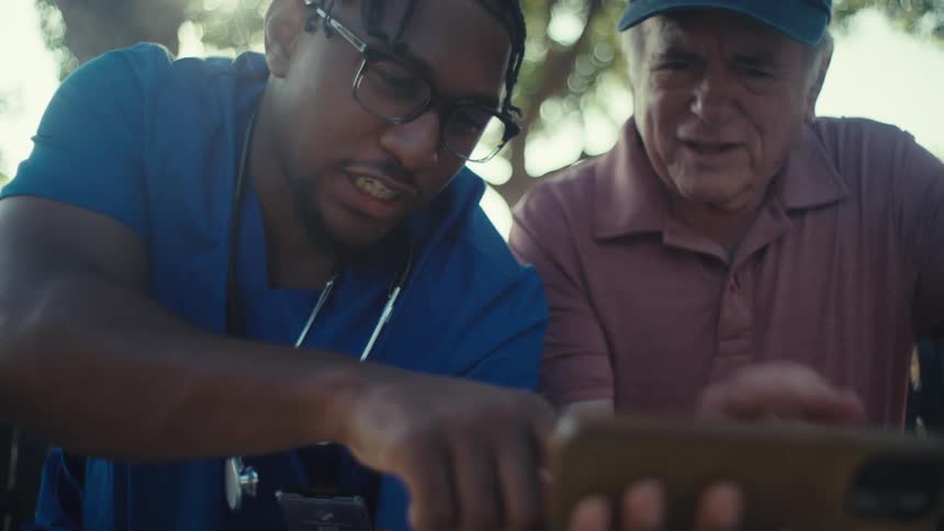 Young man and elderly man watch smartphone together outdoors