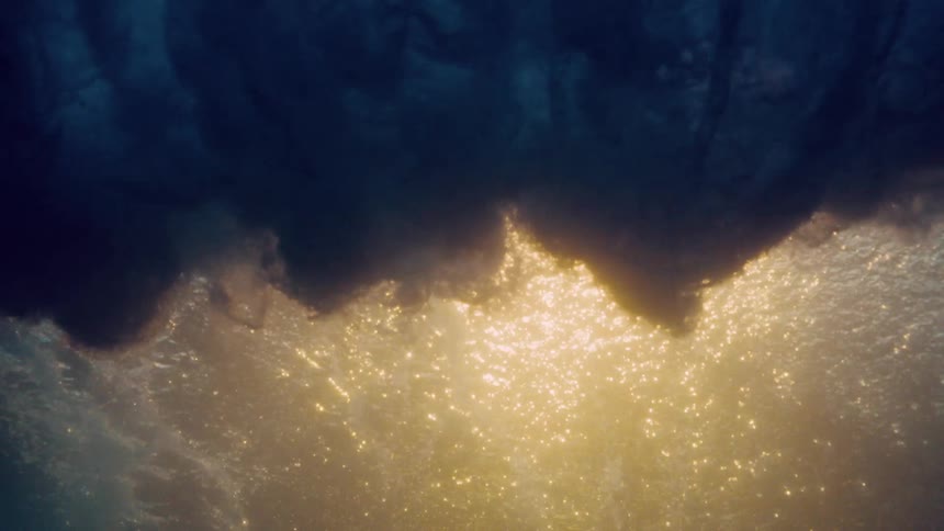 Underwater view of a strong wave with foam breaking in the ocean