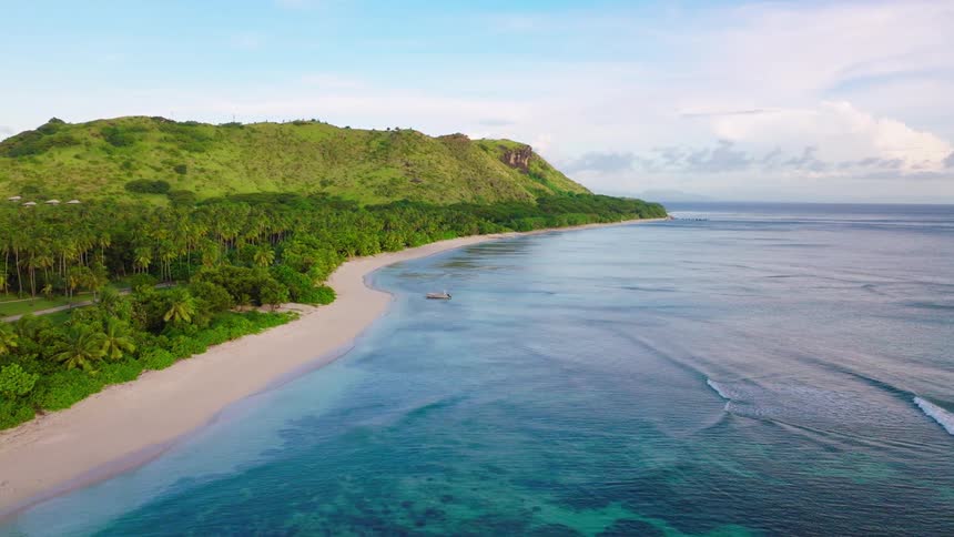 Aerial of tide gently rolling along sandy shoreline on a tropical island