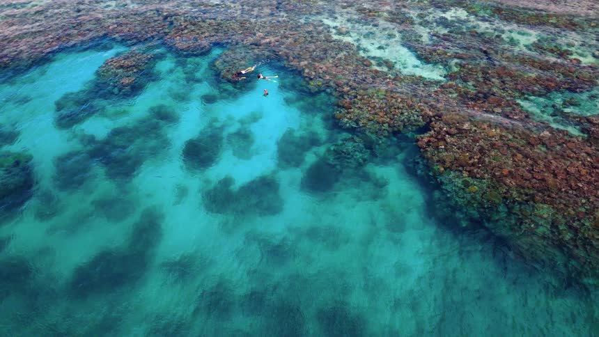People swimming in an archipelago with rocks in a turquoise blue sea