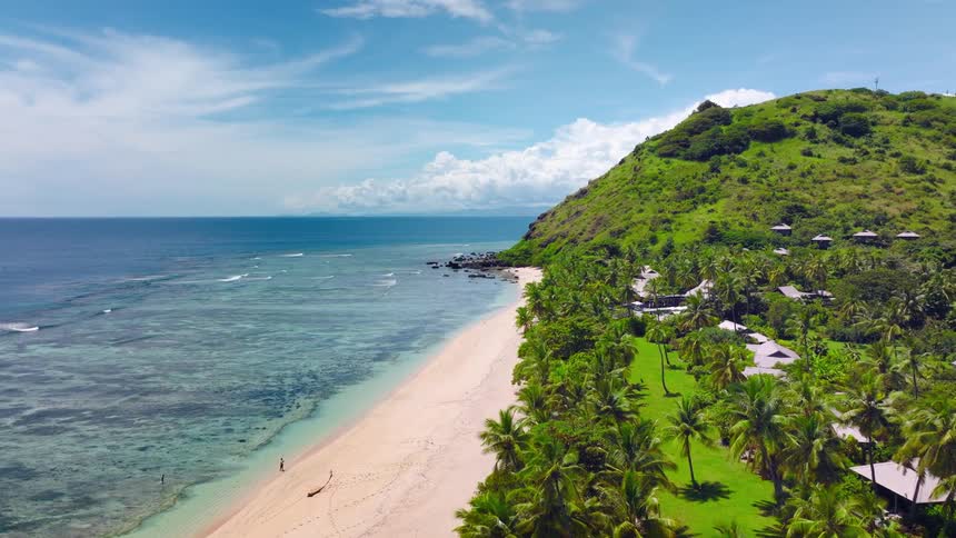 The beach is lined with palm trees and hills