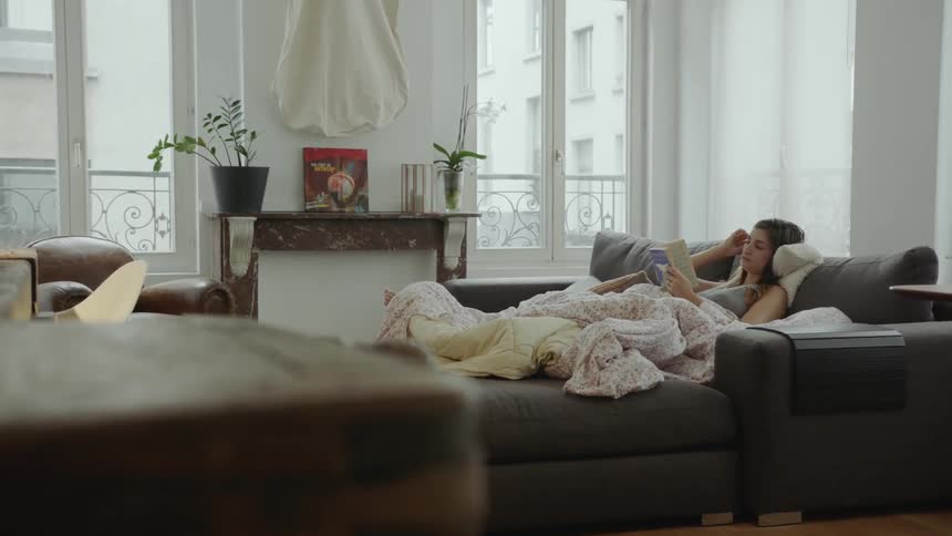A woman reads a book on her living room couch