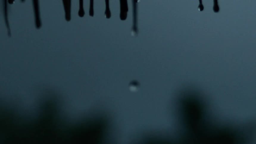 Slow motion of rain drops slowly dripping down towards the ground