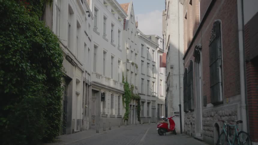 A red scooter sits on this city street