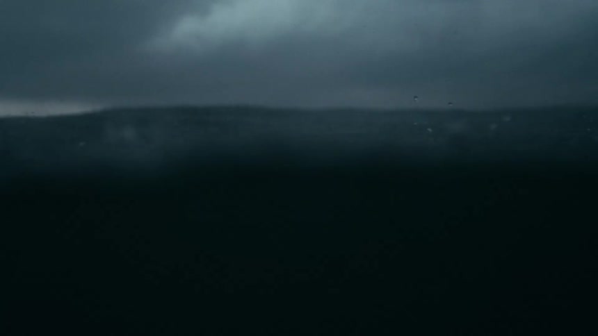 Dark choppy ocean waves churn and splash under driving rain