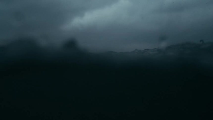 The video shows a dark stormy sea with choppy waves and heavy rainfall the horizon is barely visible through the thick grey mist and rain creating a bleak and intense atmosphere