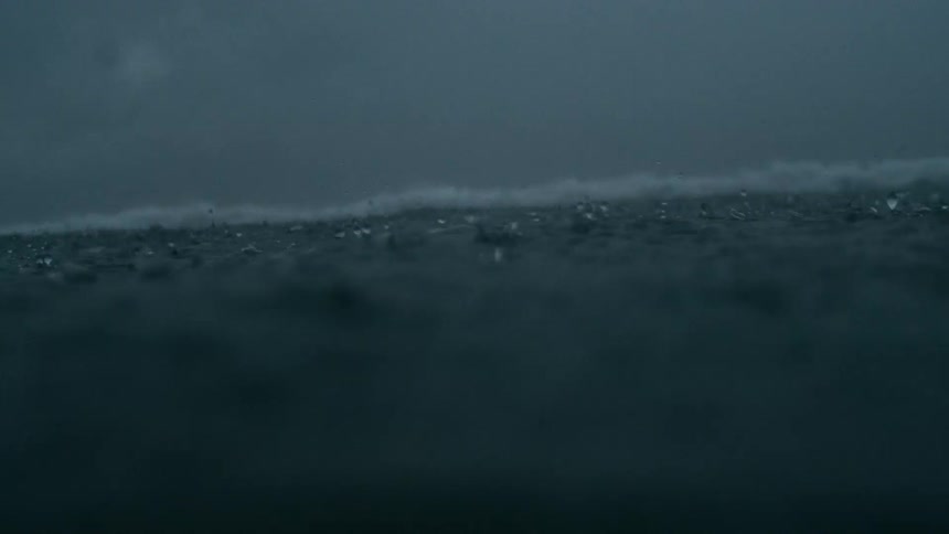 A dark murky body of water possibly an ocean or lake with the waters surface appearing rough and agitated as if in a storm or heavy rain the scene maintains a consistent dark blue or grey tone evoking a sense of solemnity or distress
