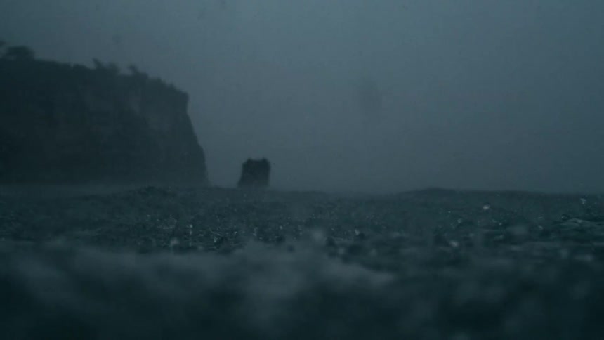 Rain storm on an ocean with the coast in the background