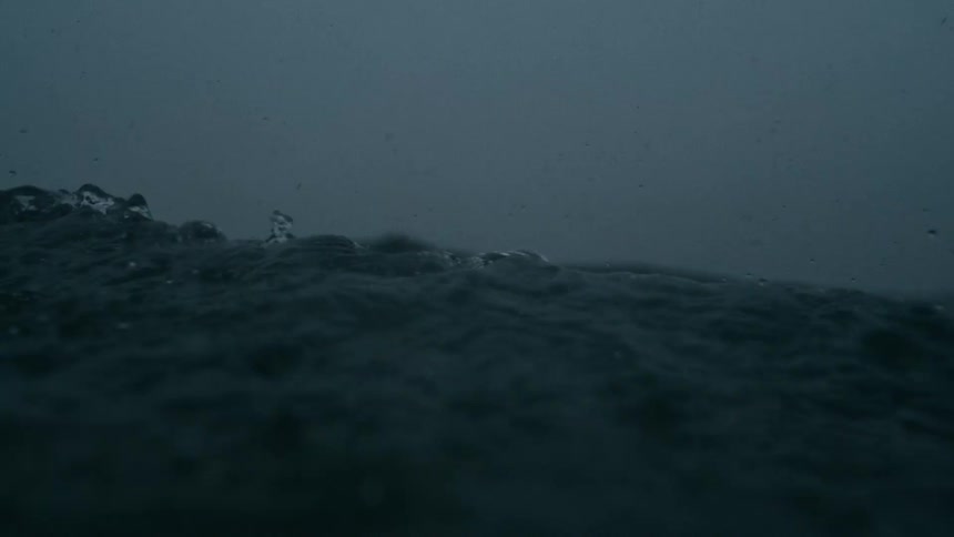 Dark turbulent ocean waves beneath a storm laden sky streaked with shifting gray clouds