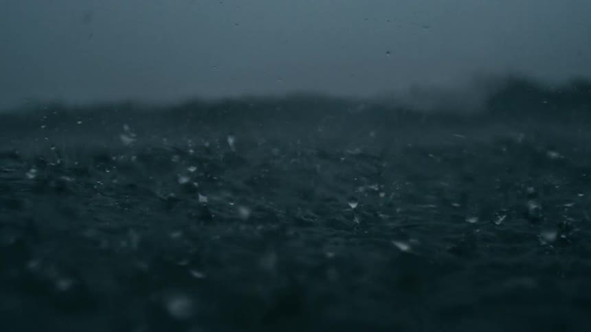 Dark choppy ocean waves churn and splash under driving rain