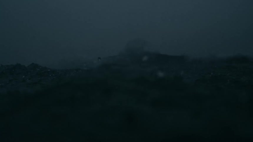 Dark choppy ocean waves churn and splash under driving rain