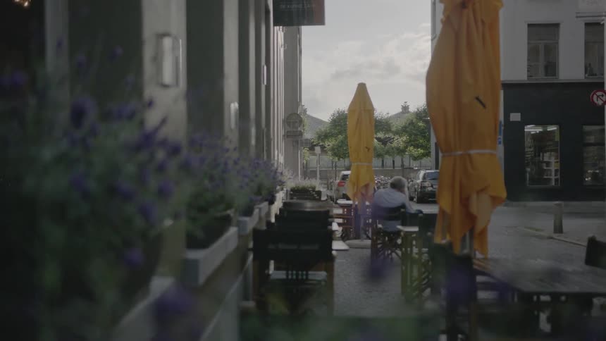 A man sits at a cafe table outdoors