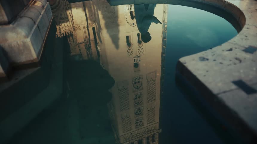 Reflection of a tall tower and a person in a still water