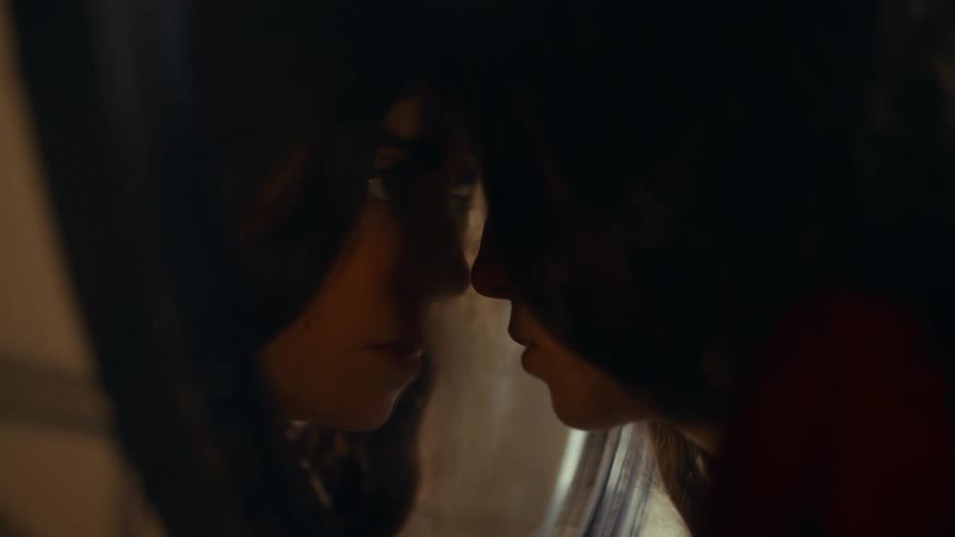 A woman leans her head into the mirror