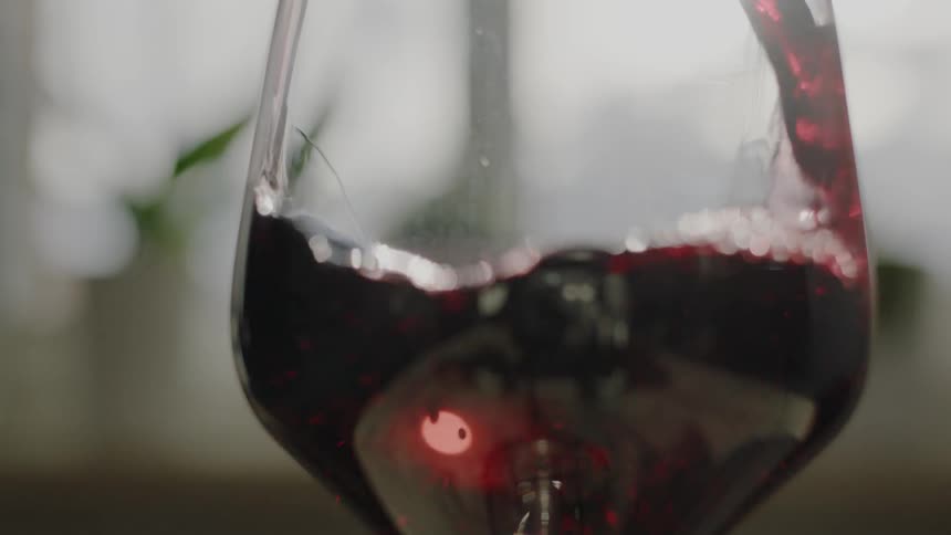 Red wine is poured into a wine glass