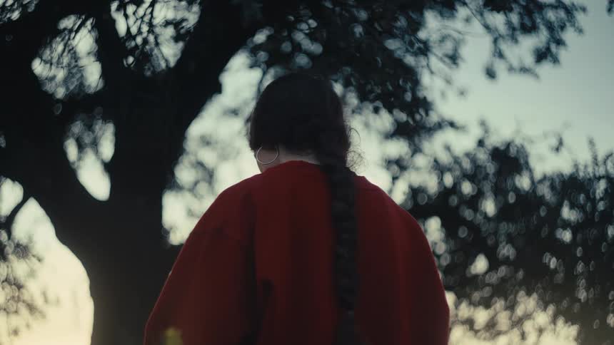 Woman with her hair tied up in an outdoor setting under a tree