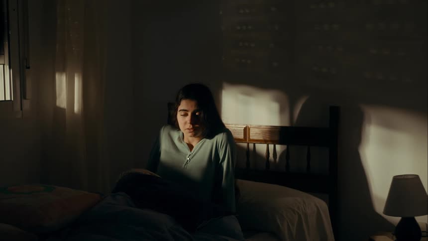 Woman waking up in bed in a dimly lit room