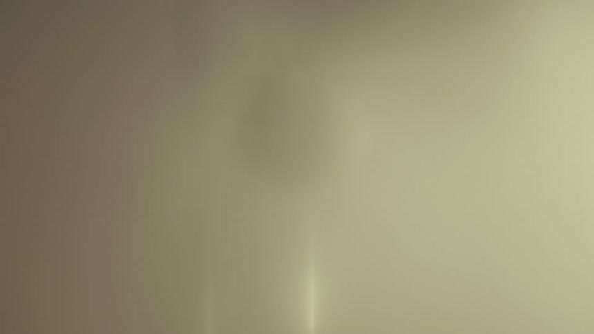 A showerhead is spraying water in a bathroom at midday