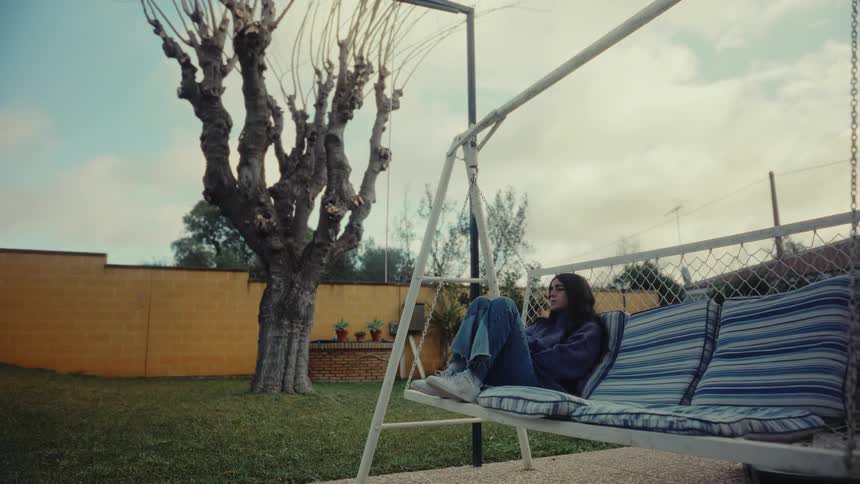 A girl sits in the swing in her yard