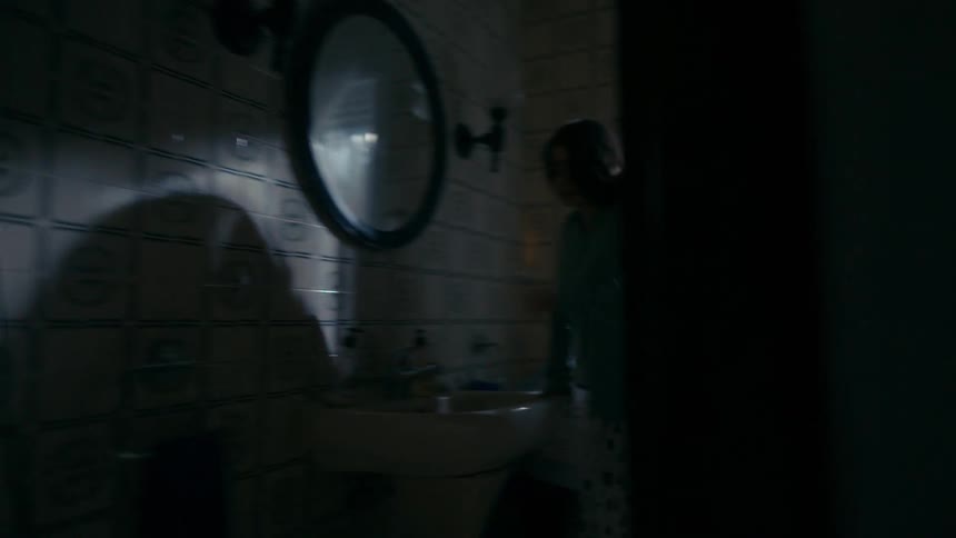 A young woman suddenly wakes up from her bed walks into the bathroom and sits on the floor crying