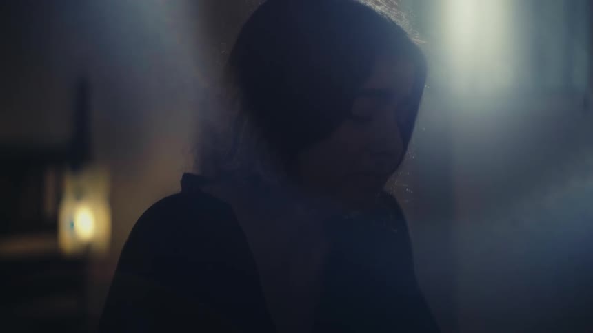 Woman in a dimly lit room expressing sadness