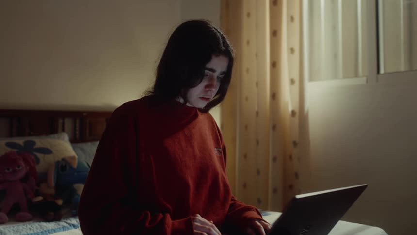 The girl uses her laptop then gets up to tear up papers