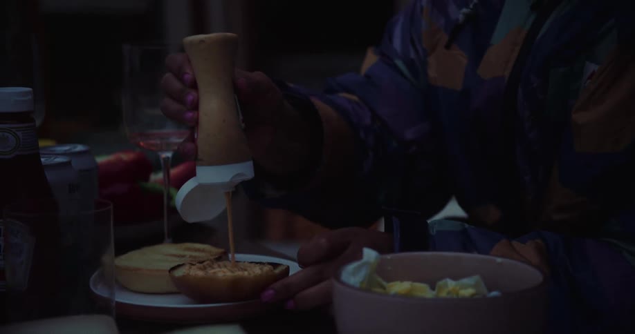 A woman puts sauce on the bun