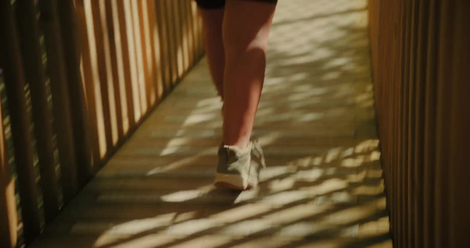 Legs of a person crossing a wooden bridge