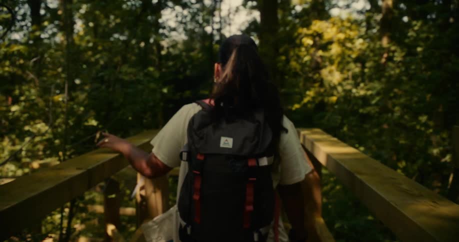 Woman with backpack crossing a wooden bridge on a forest trail