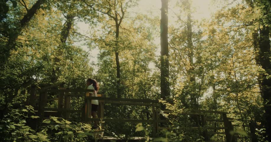 Woman crossing a wooden bridge in a forest during daytime
