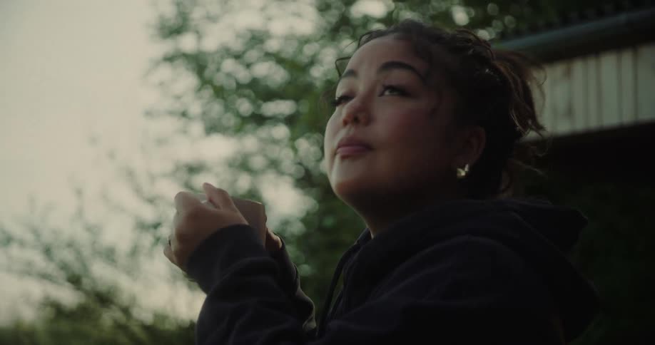 Woman outdoors holding a mug and looking around