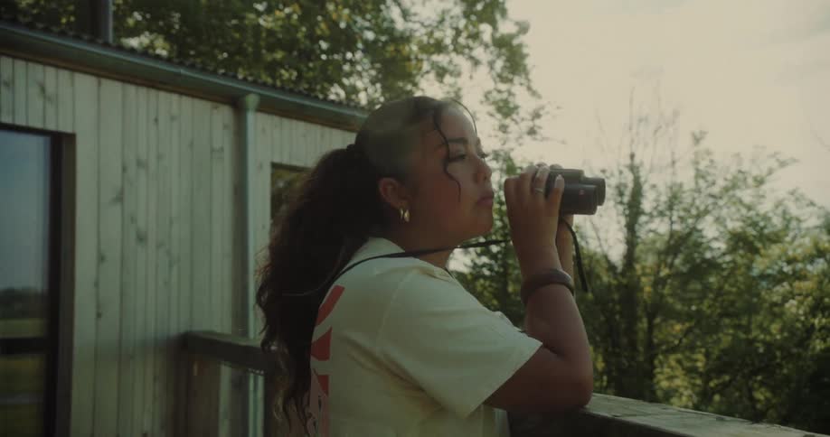 Young woman on a balcony using binoculars