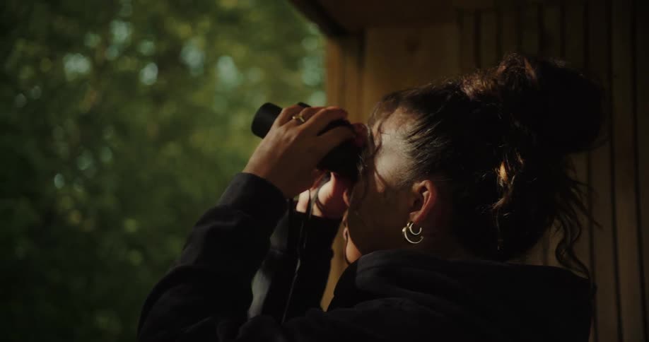 Woman on a balcony using binoculars