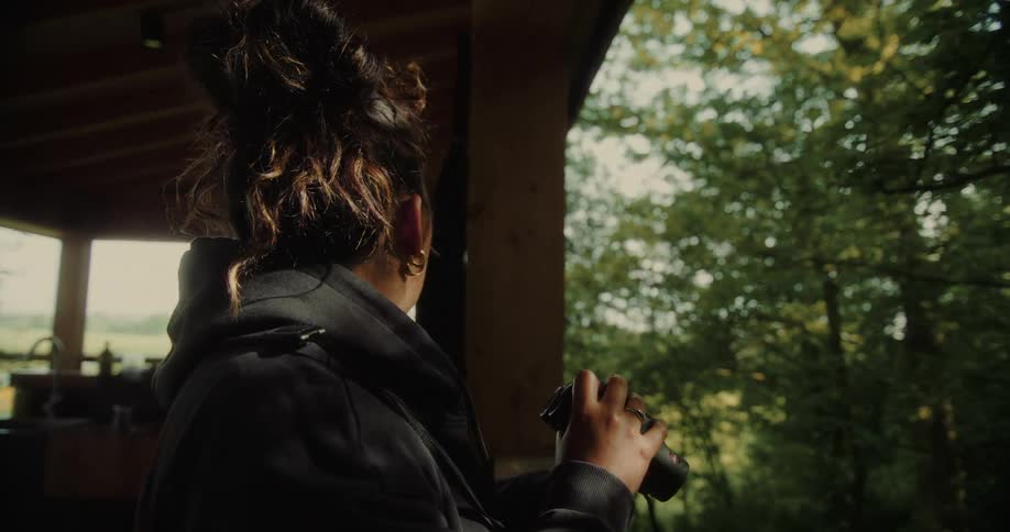The woman looks into the forest with binoculars
