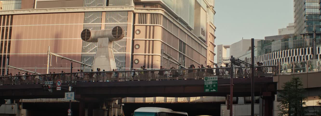 A cinematic afternoon shot of a bridge in japan. A constant crowd walk over during rush hour