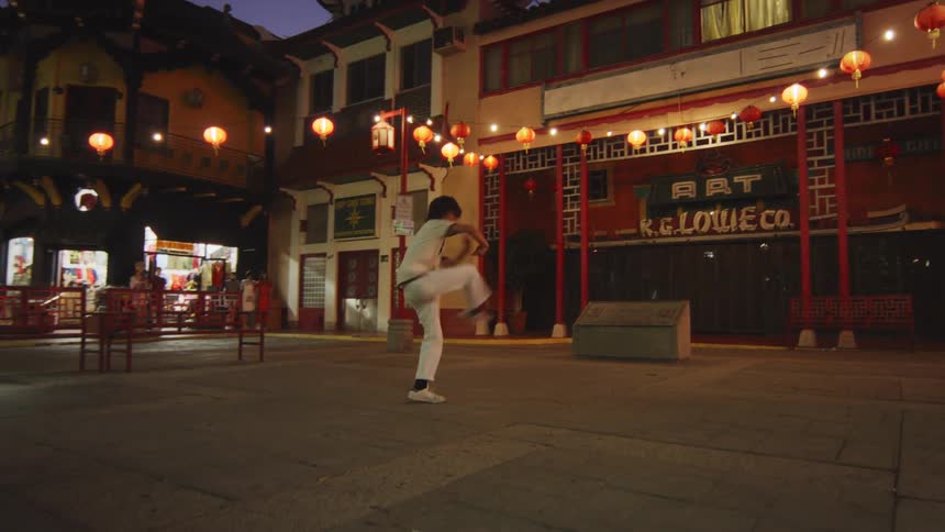 Person in a white outfit dancing in a square at night
