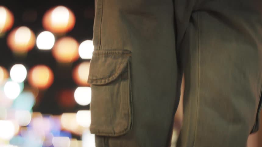 A person in cargo pants dances through a lanternlit street at night surrounded by festive hanging lights