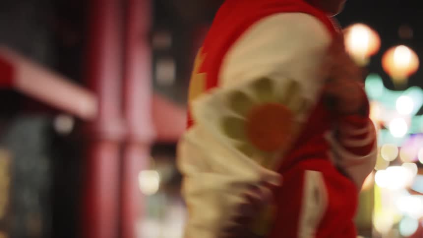 Person in red and white jacket dancing at night