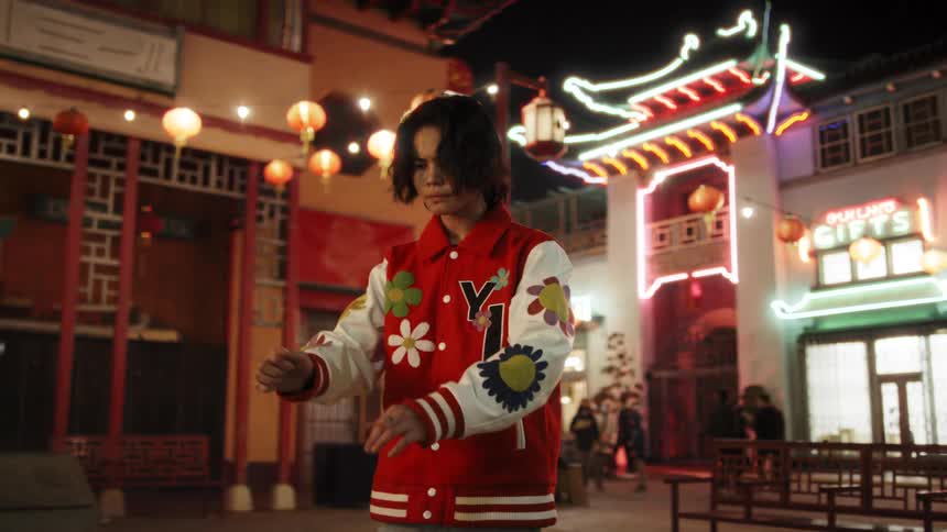 Asian teen standing in the middle of an outdoor market at night