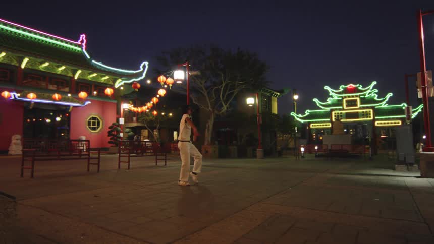 Person dancing in a public square lit up at night