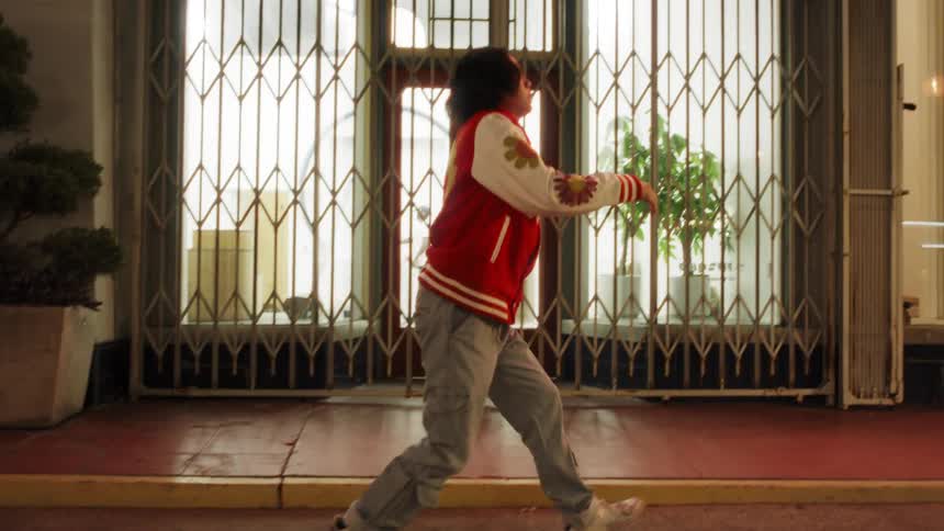 Asian teenager dancing on an urban street at night