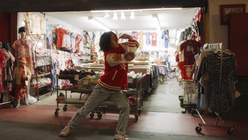 A young Asian teen dances in a street at night