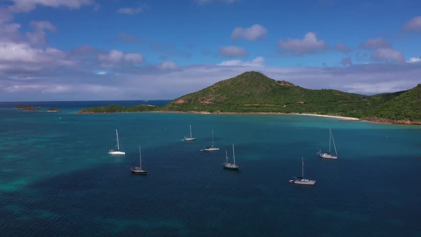 Aerial landscape of an ocean with boats and coastal mountains in the background