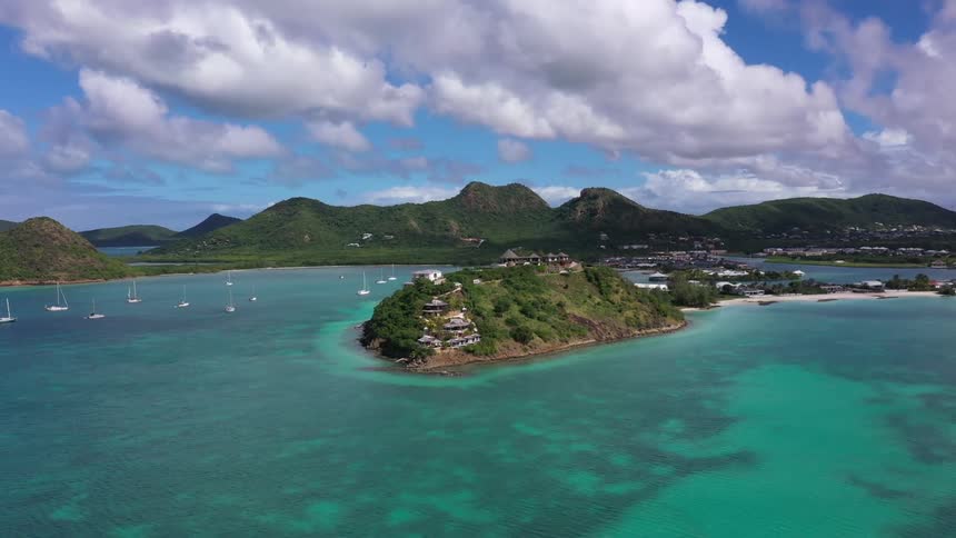 Boats float in the harbor surrounded by coastal mountains that tower over much of a coastal town