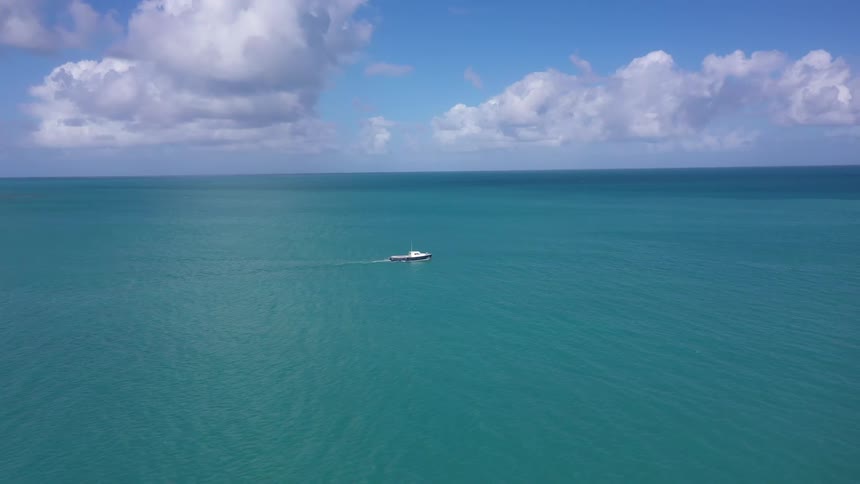 A boat is moving across the ocean at midday