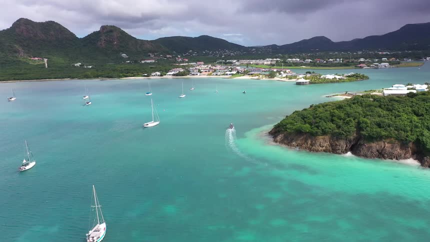 Archipelago with turquoise blue sea with boats and yachts and a village in the mountains in the background
