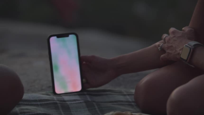 Two people are looking at a phone outside