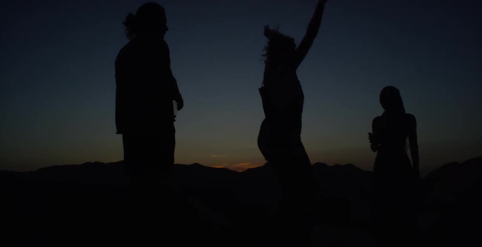 Silhouette of three people in an outdoor setting at dark dawn